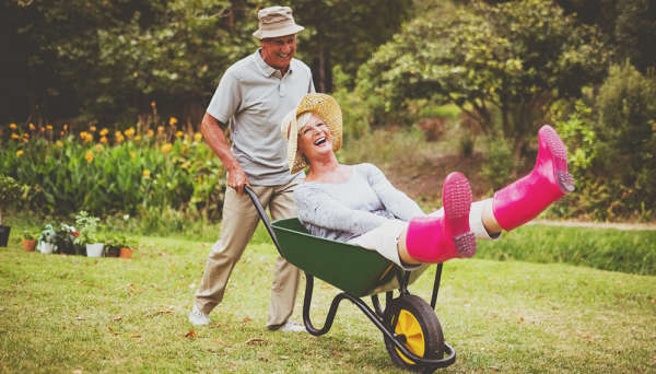 Older gentleman pushing a woman in a wheelbarrow