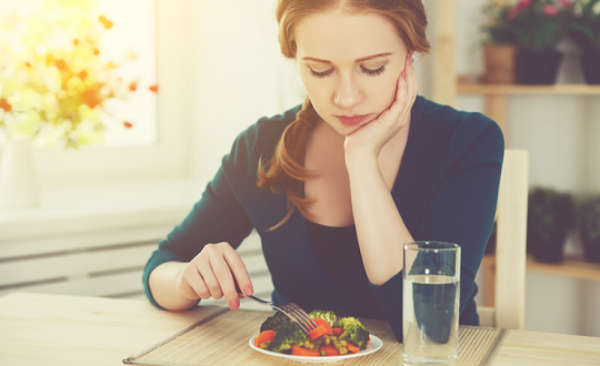 woman at dining room table eating vegetables and foods  with unsaturated fats