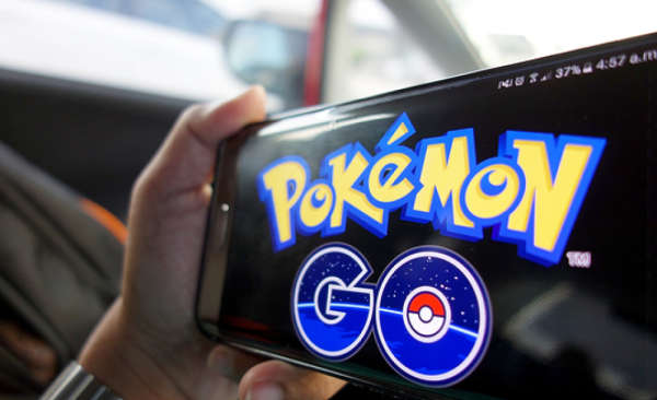 Person holding a handheld device with the Pokémon Go logo on the screen