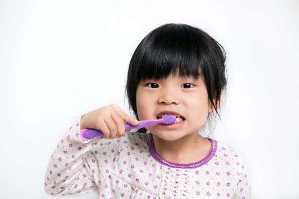 Young child, in pajamas, brushing teeth