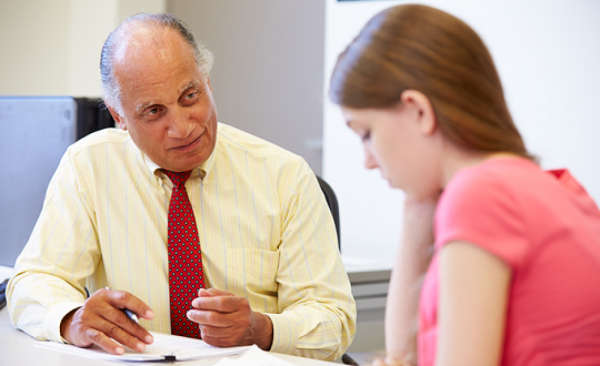 High school student sitting at a table with a school counselor