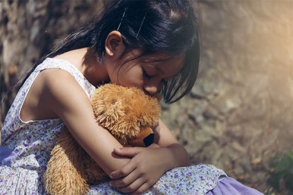 sad child separated from parents hugging teddy bear